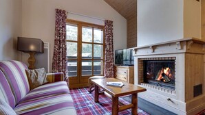 A cozy living room with a plaid carpet, a sofa, a wooden table, and a fireplace.