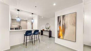 A modern kitchen with a dining area, a large abstract painting, and a minimalist design.