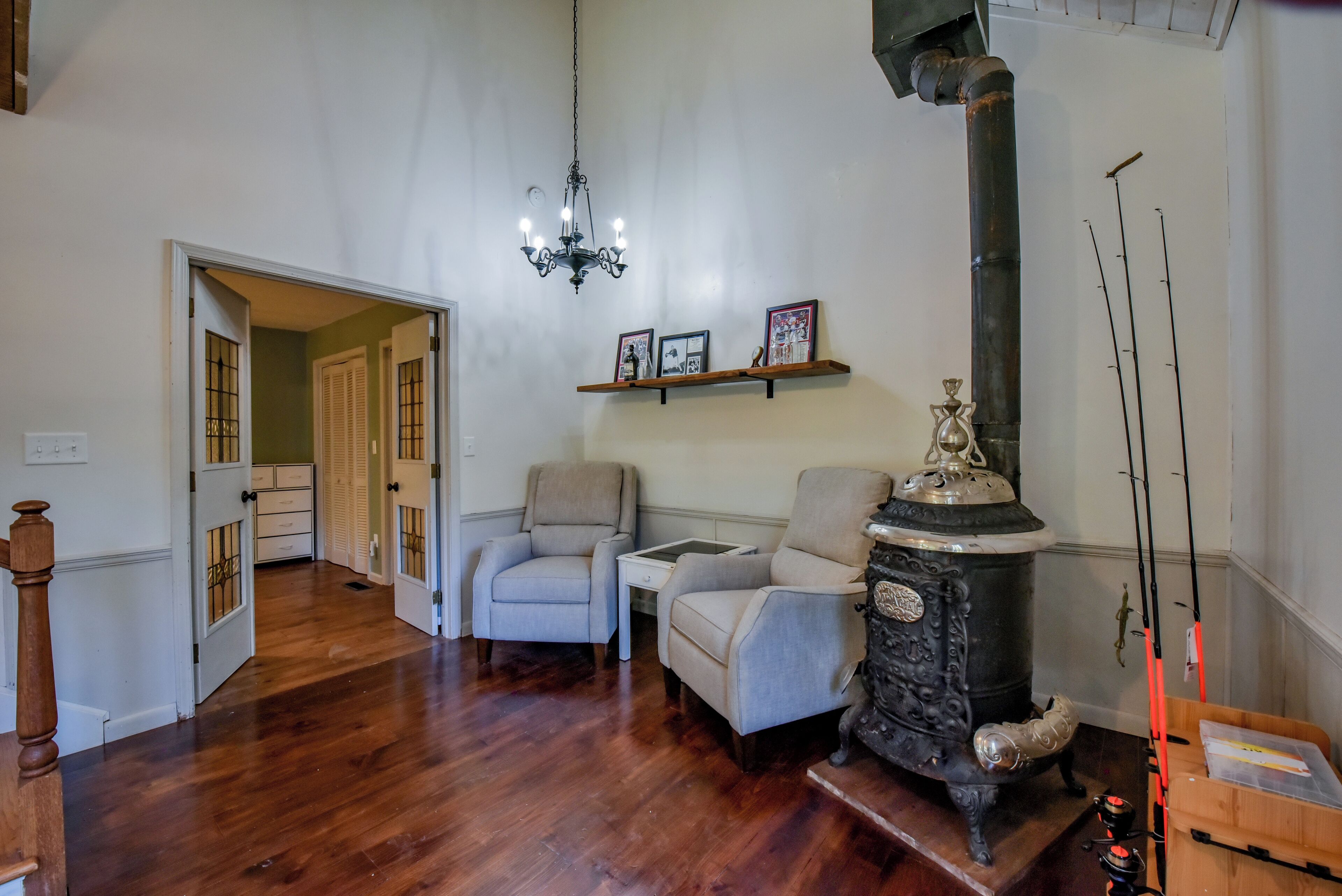 Una habitación con piso de madera, una chimenea, dos sillones, una mesita y un candelabro.