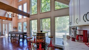 A spacious room with large windows, a wooden pool table, red stools, and a coffee machine. - Legends Lodge: A woodland retreat near University of Alabama! (Cottondale)