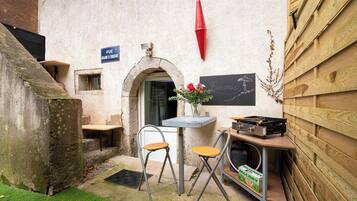 Une petite cour avec une table et deux chaises, un tableau noir avec des inscriptions et une enseigne indiquant « RUE ».