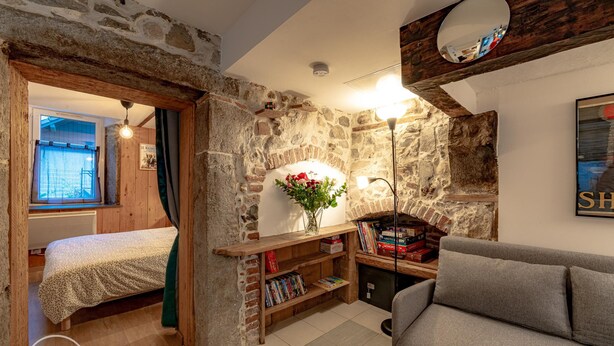 A cozy room with a bed, a sofa, a bookshelf, and a stone wall. - The refuge at the end of the world (saint alban leysse)