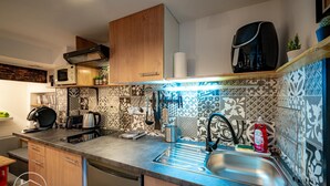 A modern kitchen with a stainless steel sink, wooden cabinets, and patterned backsplash tiles. - The refuge at the end of the world (saint alban leysse)