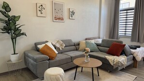 Un salon moderne avec un canapé gris, une table basse ronde et une plante en pot.