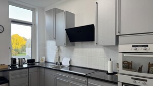 Une cuisine moderne dotée d’appareils électroménagers en acier inoxydable, d’une grande fenêtre et offrant une vue sur un arbre à l’extérieur.