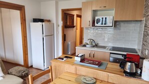 A compact kitchen with a refrigerator, microwave, sink, and a small dining area with a table and chairs. - 2 bedroom appt 20 mins from Morzine and rest of Portes du Soleil (Le Biot)