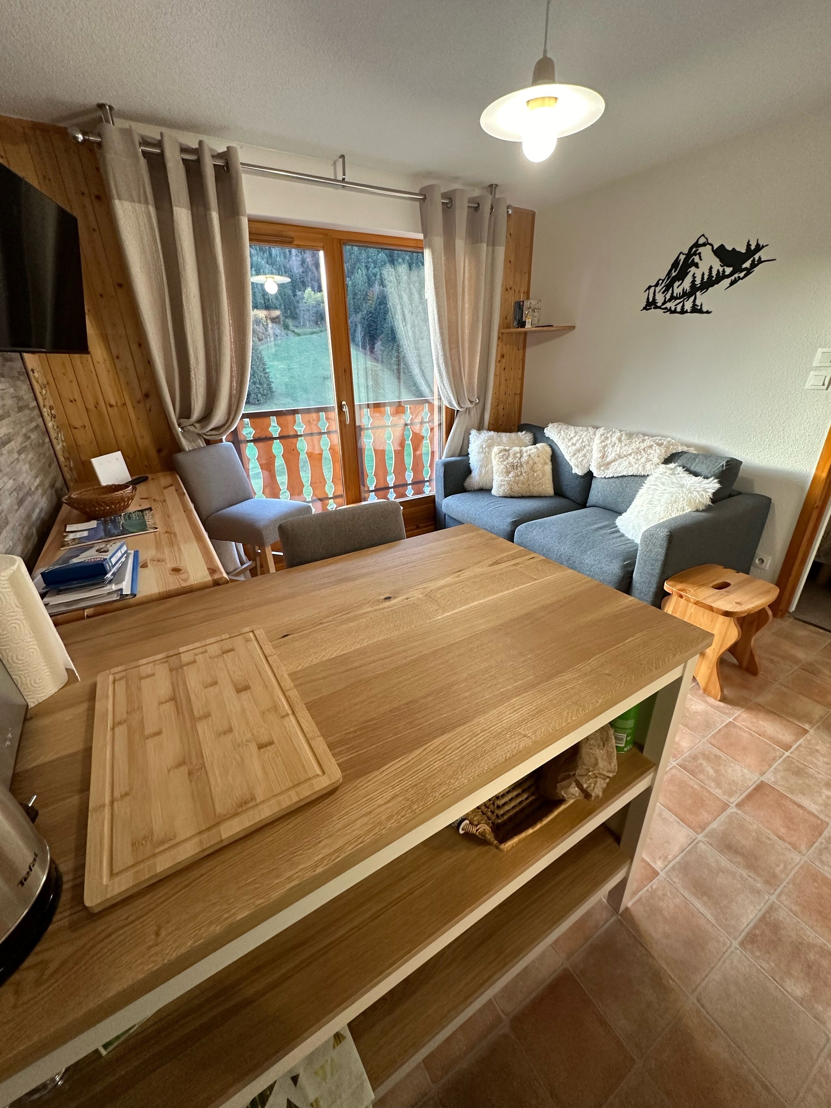 Un espacio acogedor con una mesa de madera, un sofá y un taburete pequeño de madera.