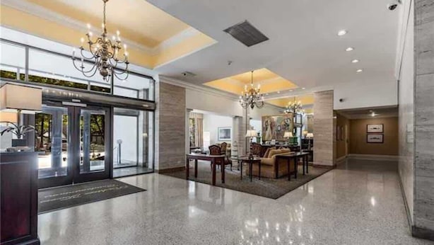 A spacious lobby with a polished floor, a reception desk, and a seating area with a chandelier.
