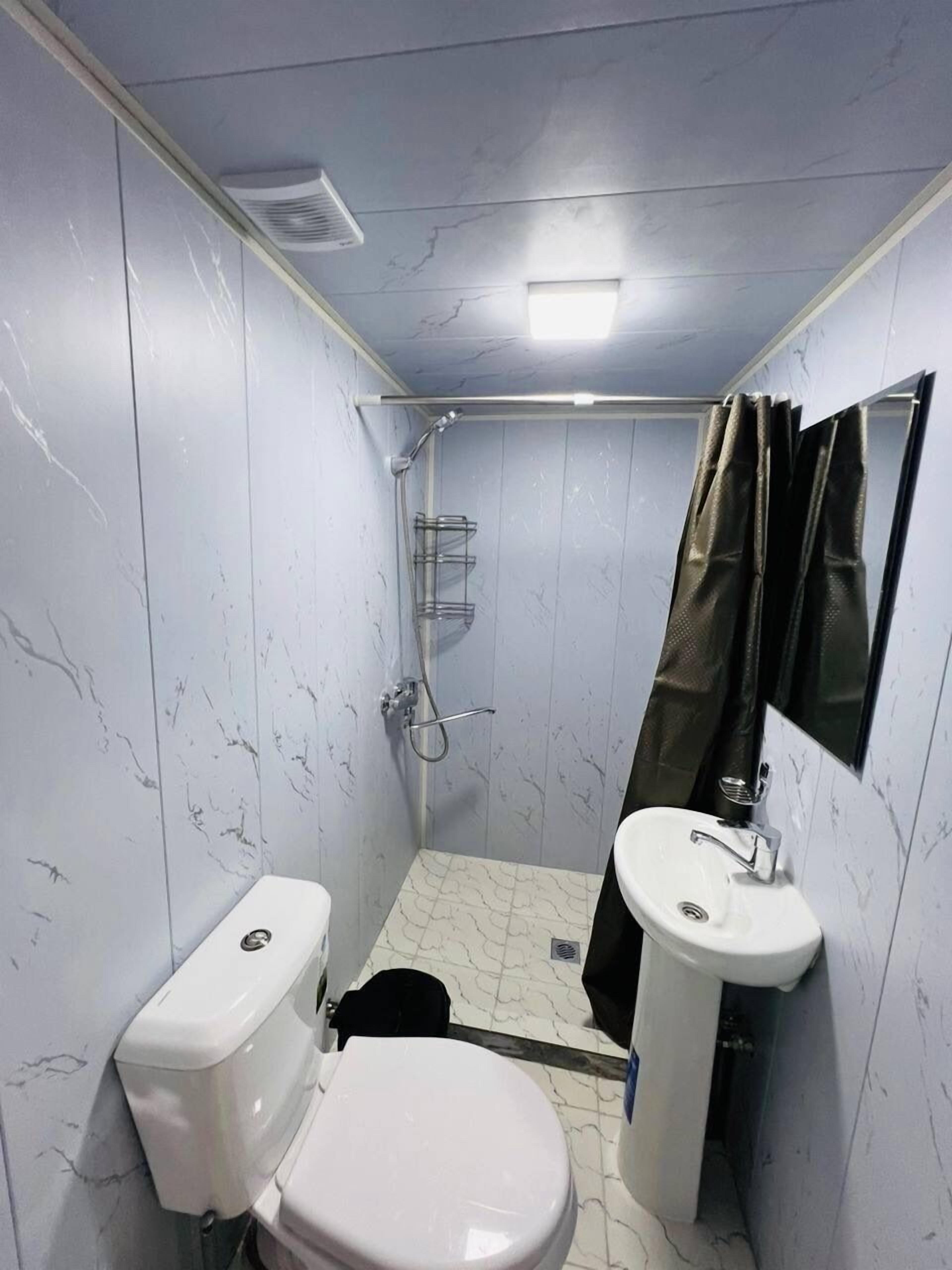 A small bathroom with a toilet, sink, and shower.