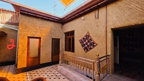 Un patio con piso de baldosas, baranda de metal y pared con diseño.