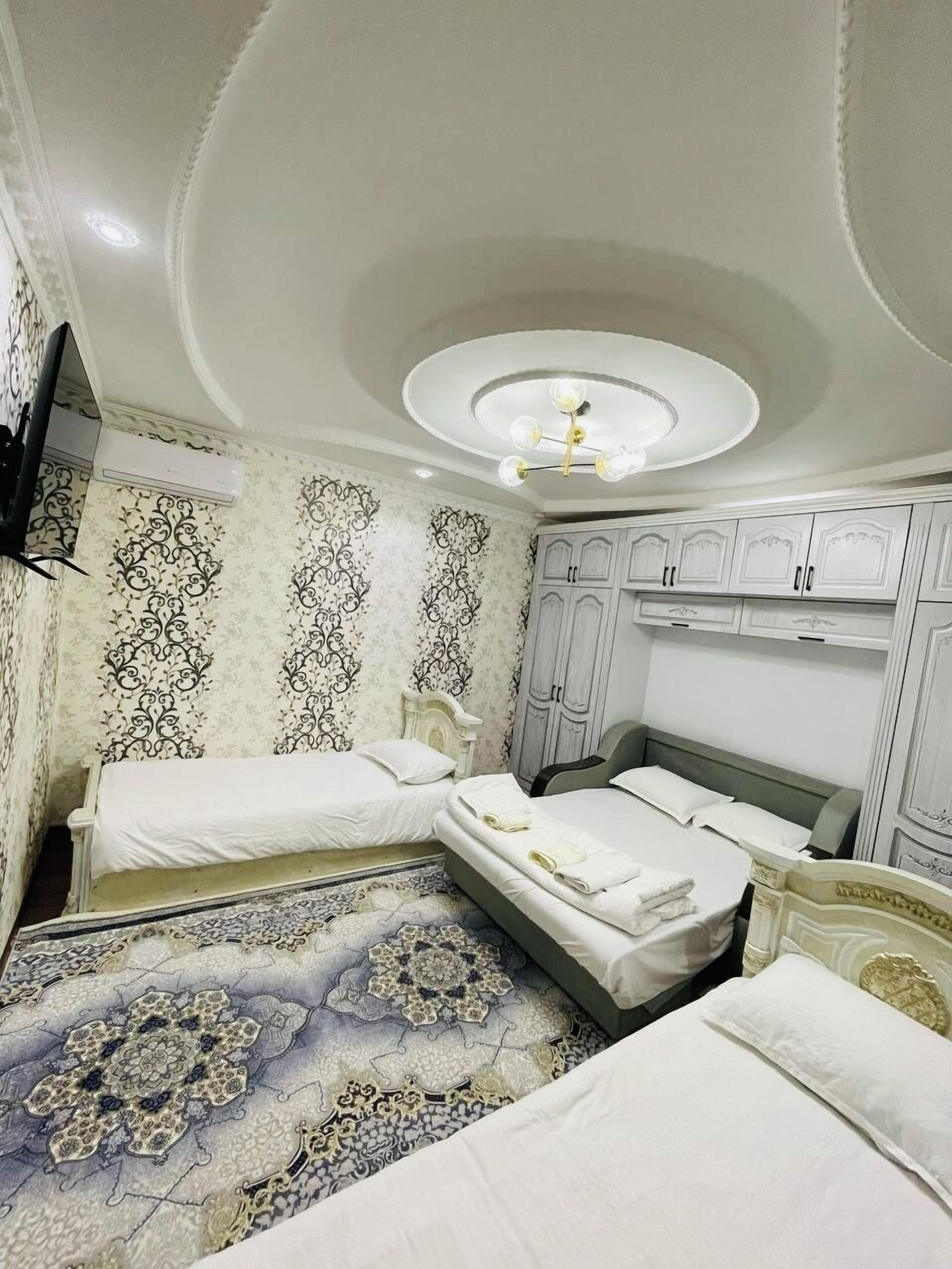 Habitación de hotel con dos camas individuales, un espejo grande y una lámpara en el techo.