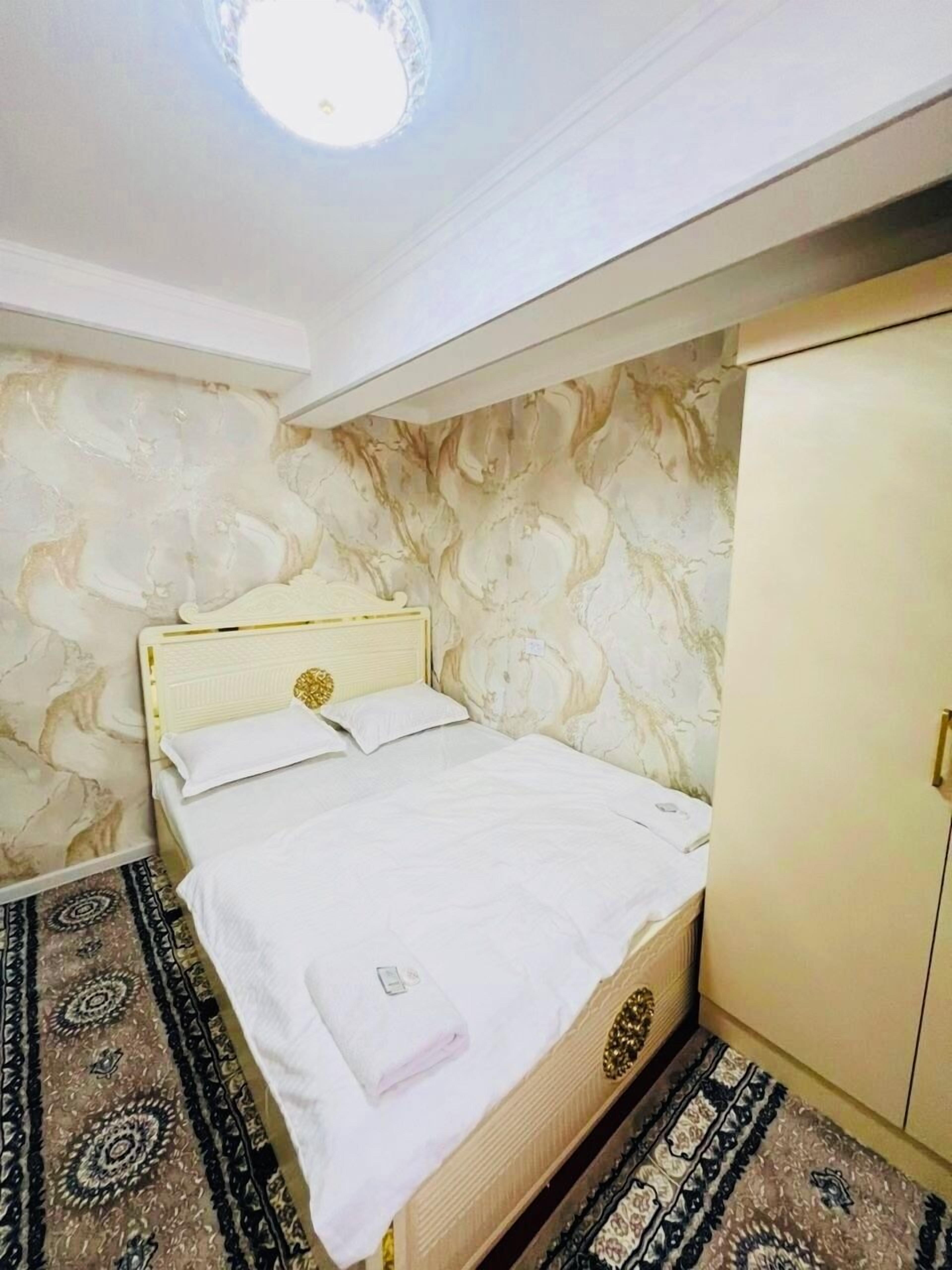 A bedroom with a bed, a wardrobe, and patterned walls.