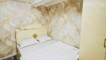 A bedroom with a bed, a wardrobe, and patterned walls.