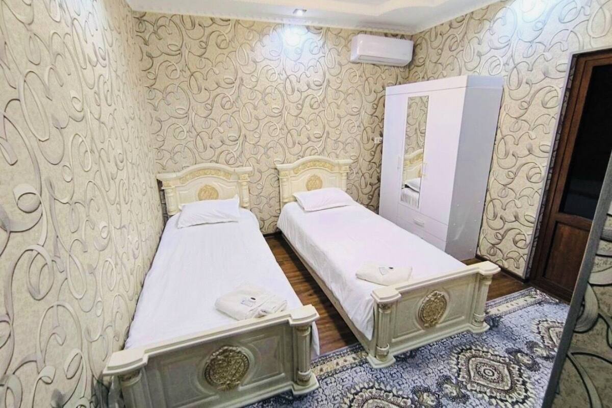 A room with two single beds, a wardrobe, and patterned wallpaper.