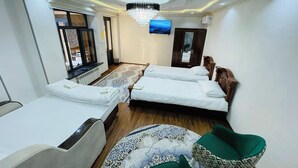 Habitación de hotel con dos camas, televisión, candelabro y alfombra estampada.