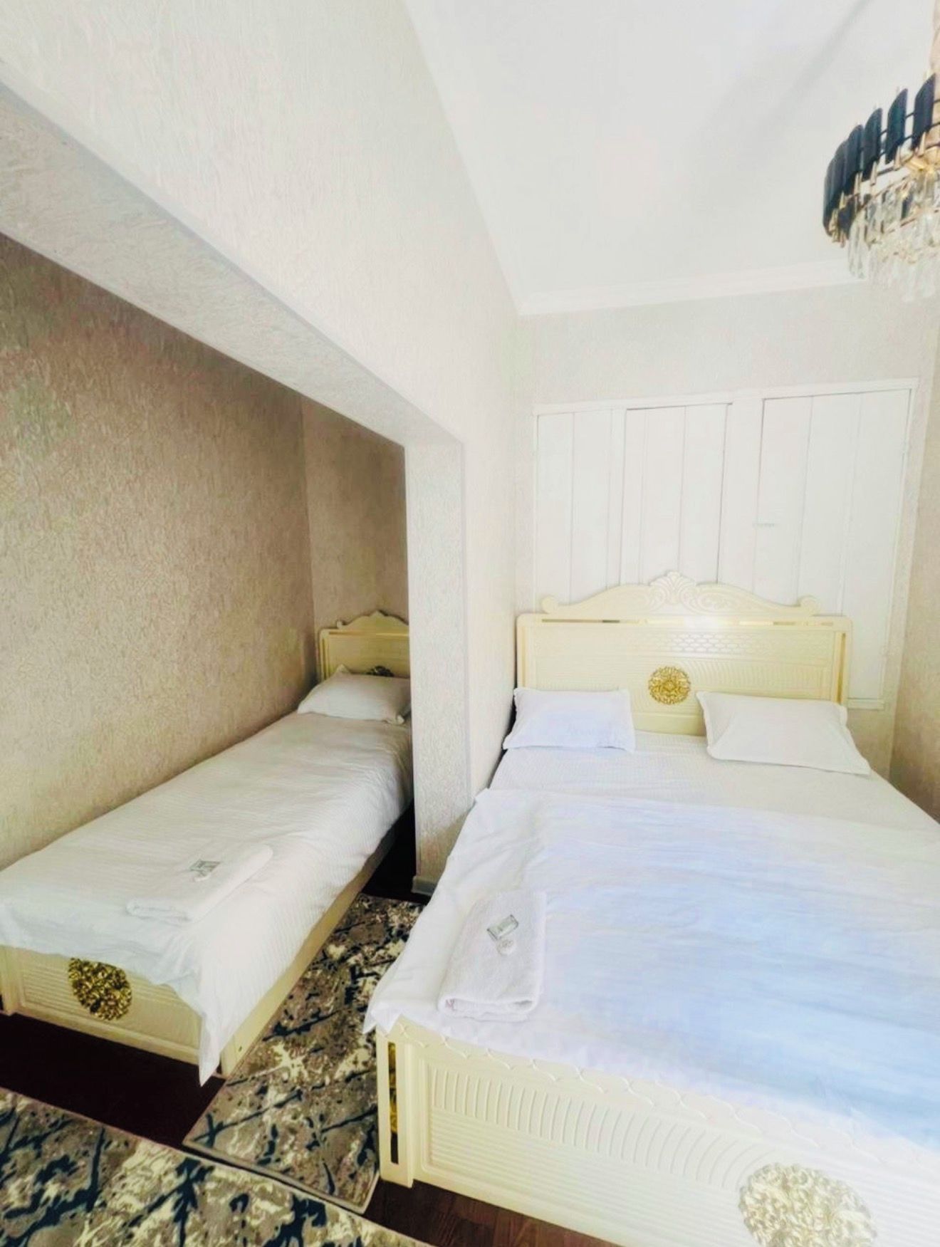 Una habitación de hotel con dos camas individuales, una cama grande y un candelabro.