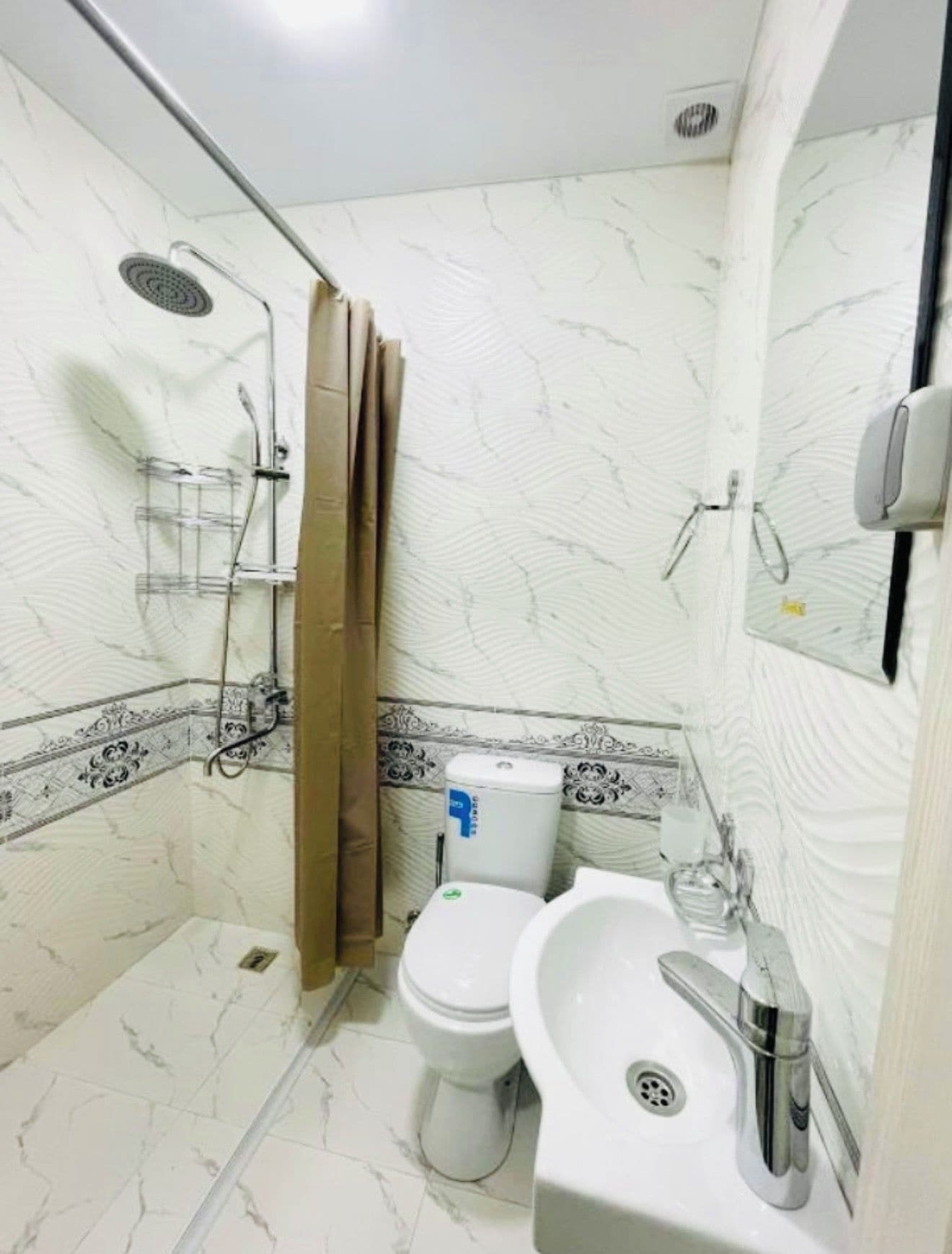 Une salle de bain avec douche, toilettes et lavabo.