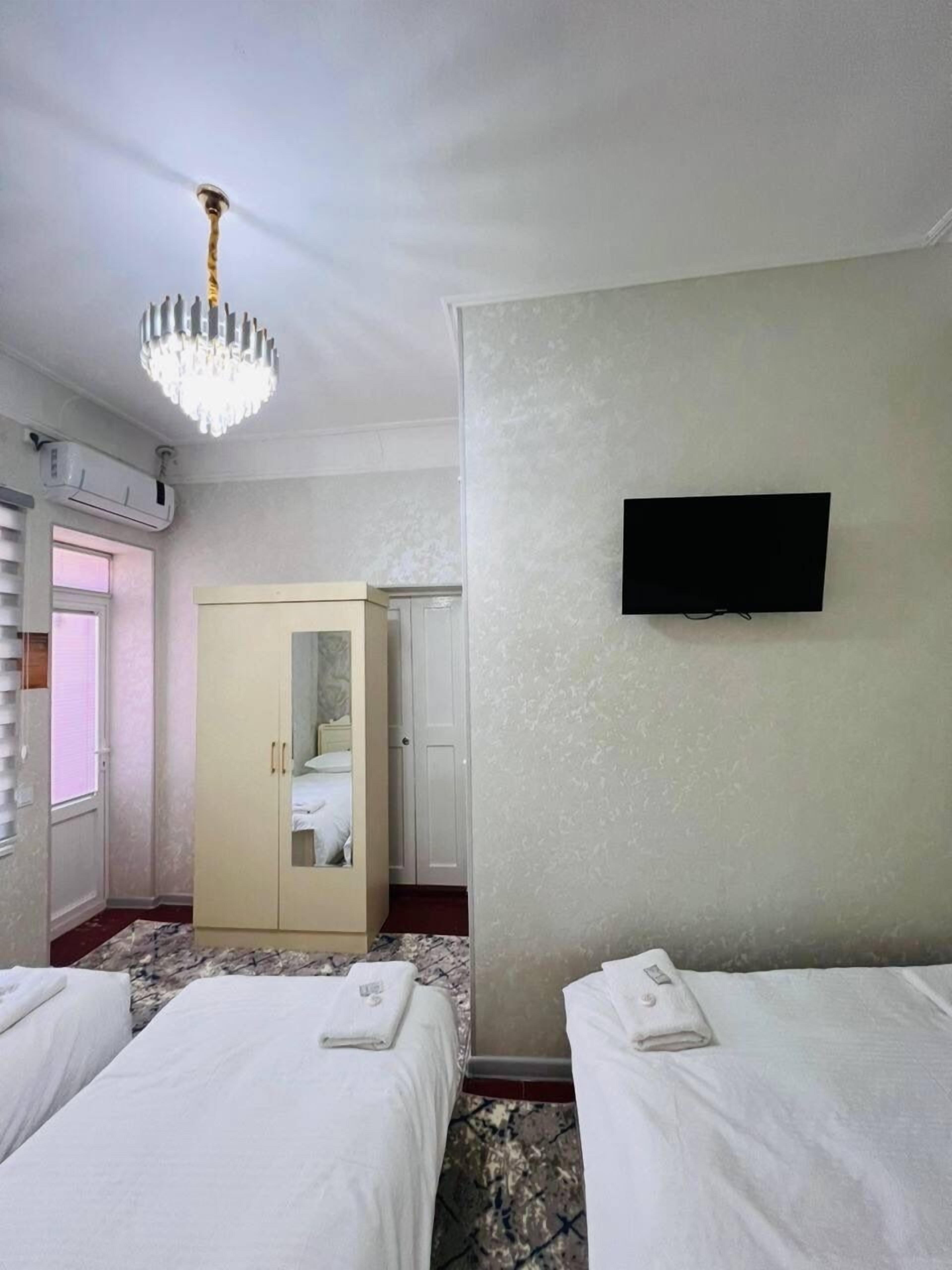 Habitación de hotel con dos camas, un armario, un televisor en la pared y un candelabro.
