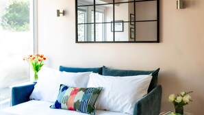 Une chambre à coucher avec un lit, une table de chevet ornée d’un vase et un grand miroir au mur.
