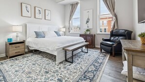 A bedroom with a bed, bedside tables, a chair, a rug, and framed artwork on the walls. - Heron’s Perch - Uptown Port Clinton, Jet Express, 5 minute walk to Beach (Port Clinton)
