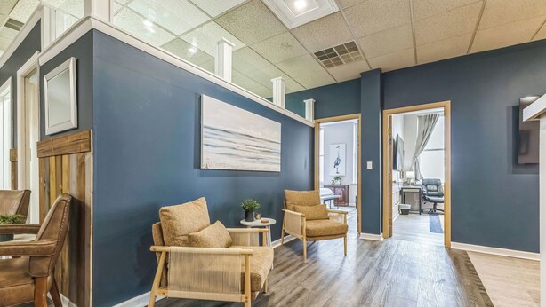 A spacious room with a dark blue wall, a large window, and a wooden floor. - Heron’s Perch - Uptown Port Clinton, Jet Express, 5 minute walk to Beach (Port Clinton)