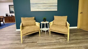 A room with two armchairs facing each other, a small round table with a plant, and a painting of a beach scene on the wall. - Heron’s Perch - Uptown Port Clinton, Jet Express, 5 minute walk to Beach (Port Clinton)