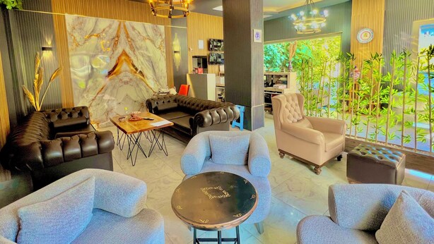 A modern living room with a sectional sofa, armchairs, a coffee table, and a chandelier.