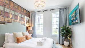 Ein modernes Hotelzimmer mit einem großen Bett, einem an der Wand montierten Fernseher und Blick auf die Stadt durch große Fenster.