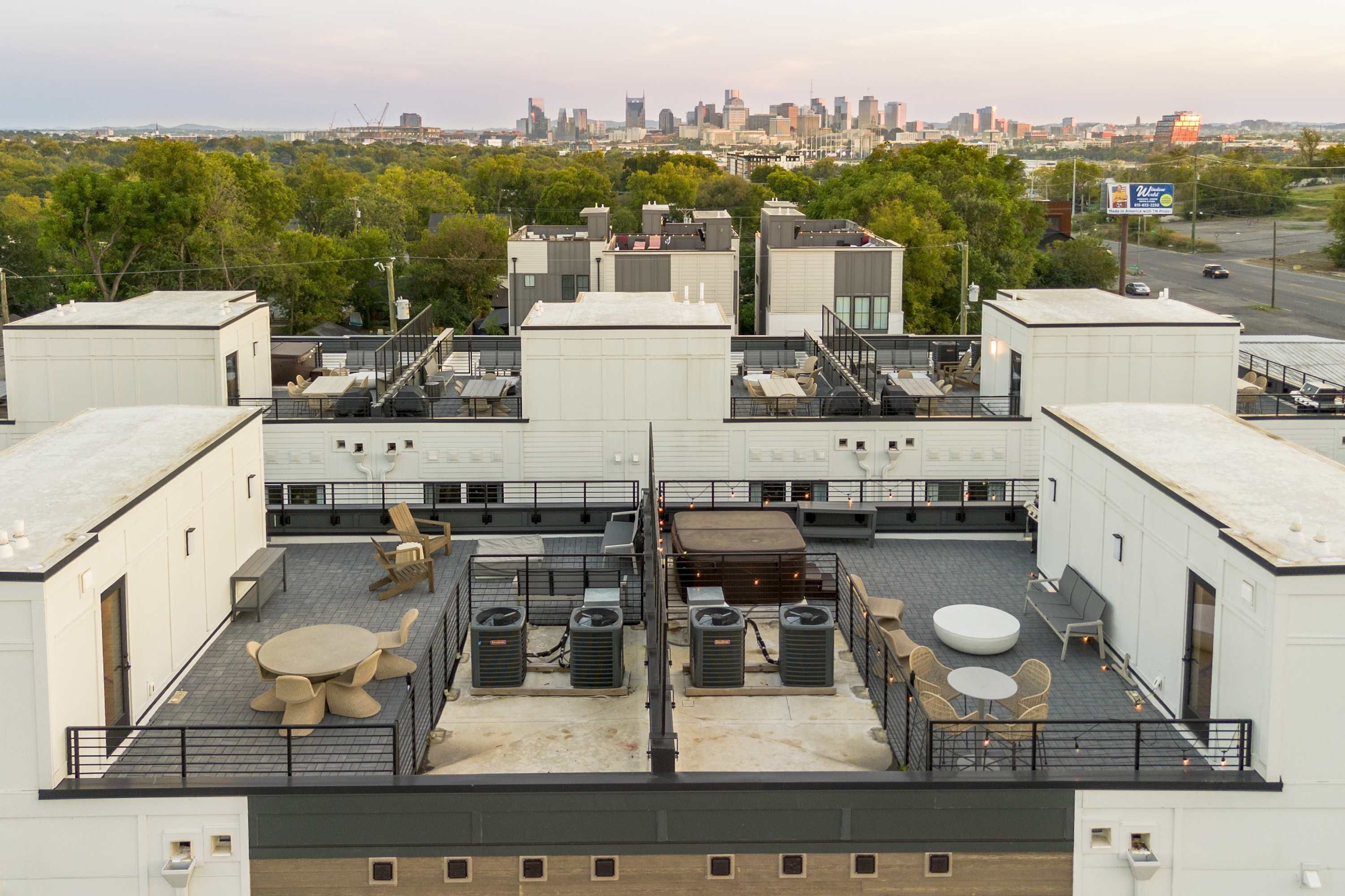 Terraço no telhado com área de refeições, aparelhos de ar condicionado e vista do horizonte da cidade.