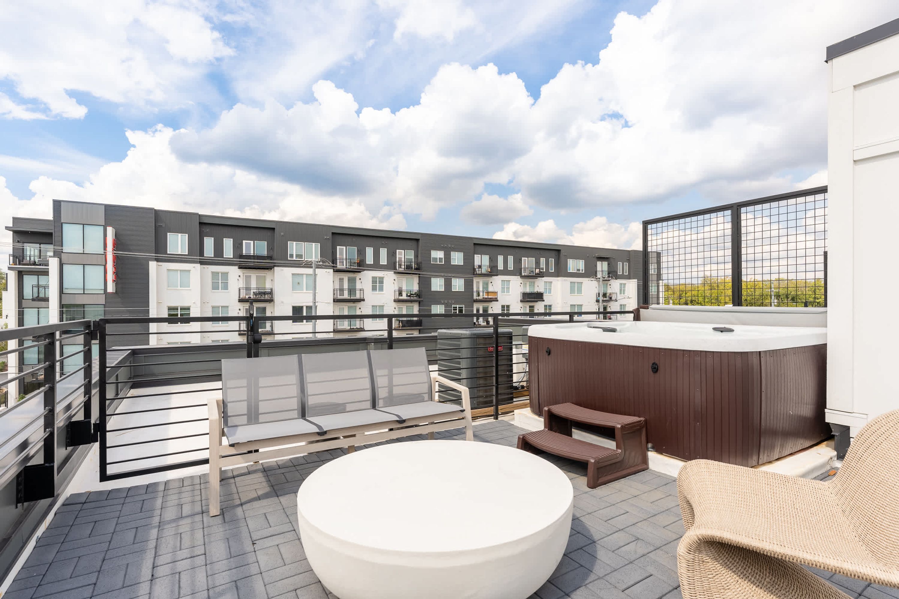 Eine Dachterrasse mit Sitzgelegenheiten im Freien, einem Whirlpool und Blick auf moderne Wohngebäude.
