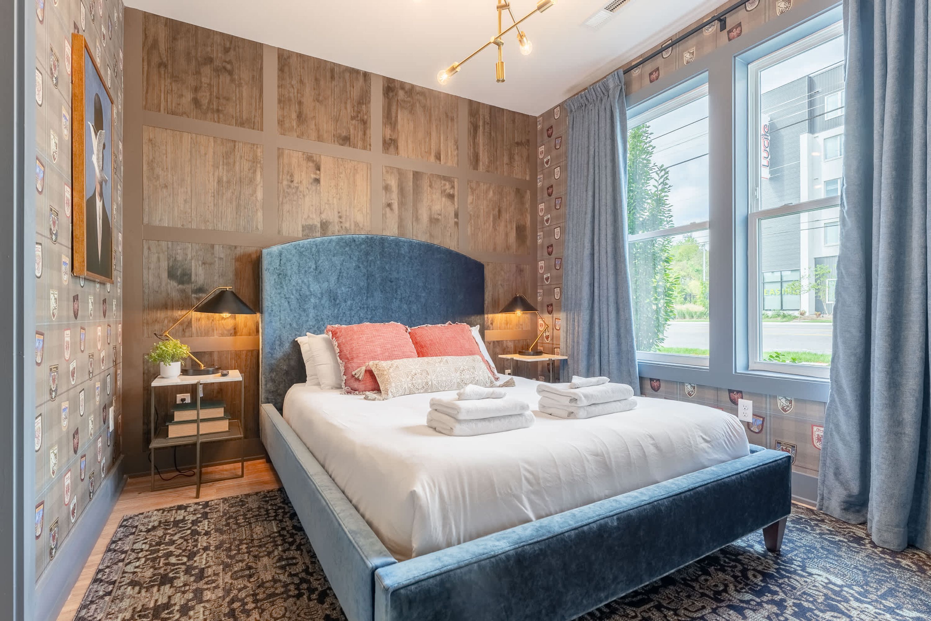 Een moderne slaapkamer met een groot bed, een houten accentmuur en uitzicht op het omliggende landschap.