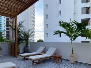 Une terrasse sur le toit, avec deux chaises longues, une petite table et des plantes en pot.