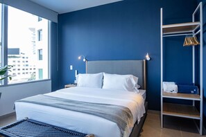 Une chambre d’hôtel moderne dotée d’un grand lit, d’une table de chevet, d’une commode, d’une armoire et offrant une vue sur la ville.