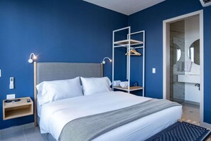 Une chambre d’hôtel moderne dotée d’un grand lit, de tables de chevet, d’une armoire et d’une salle de bain avec une douche en verre.