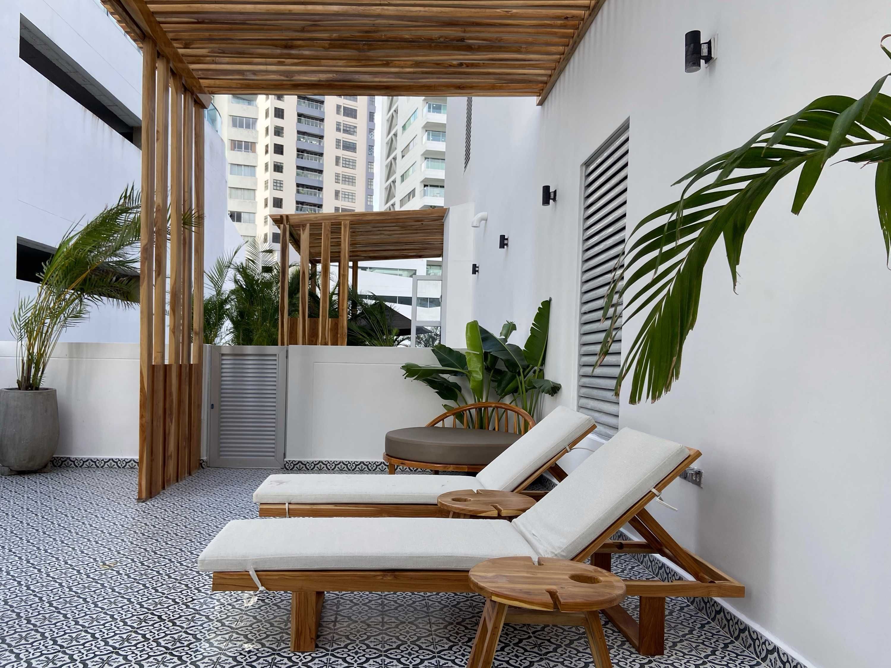 Une terrasse sur le toit, avec deux chaises longues, une pergola en bois et des plantes en pot.