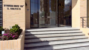 The entrance to Wynwood House 109 with a glass door, brick facade, and steps leading up to the entrance. - w Cozy 2BR w Balcony in Santa Barbara (Bogotá)