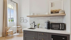 Een moderne keuken met een wit aanrecht, donkere kastjes, een magnetron en een koffiezetapparaat.