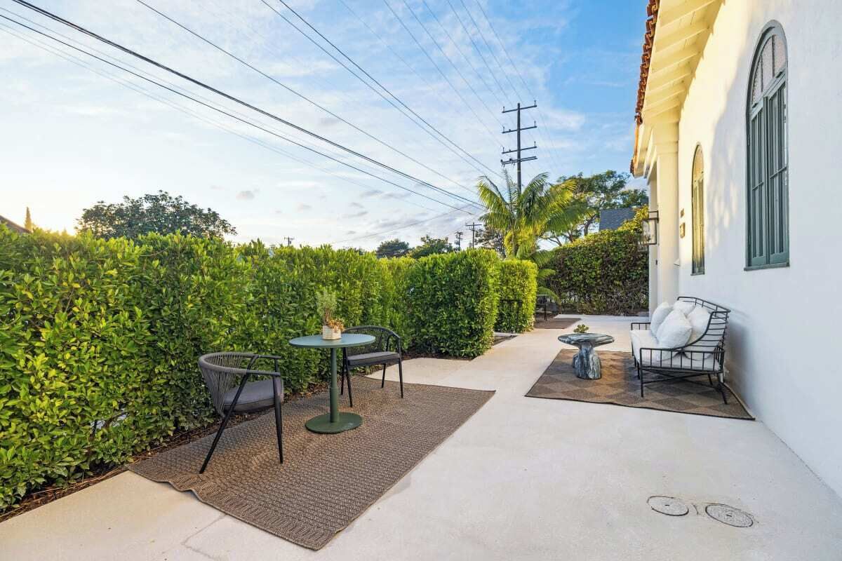 An outdoor patio with a table and chairs, a small round table, and a sofa.