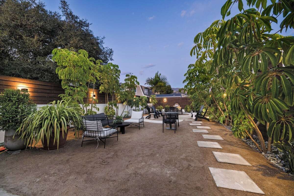 A patio area with outdoor seating, potted plants, and a stone pathway.