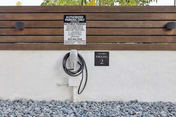 Un panneau de signalisation indiquant un espace de stationnement avec une borne de recharge et un panneau portant le numéro 2, le tout fixé à un mur.