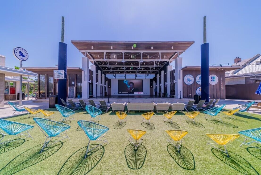 An outdoor amphitheater with a stage, seating, and colorful chairs.