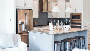A modern kitchen with stainless steel appliances, white cabinets, and a marble island with bar stools. - Tryin' To Catch A Good Time-30A Townhome with 6-Seater Golf Cart! Sleeps 8 (Santa Rosa Beach)