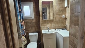 A compact bathroom with a toilet, sink, and a mirror above the sink. - KNEZEVIC RESORTS 1
APARTMANI ZA ODMOR I UZIVANJE (Athina)