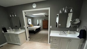 Une salle de bain moderne avec deux lavabos, un grand miroir et un dressing.