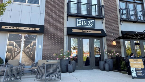Un bâtiment portant l’inscription « BIN 23 », un marché et un bistrot.
