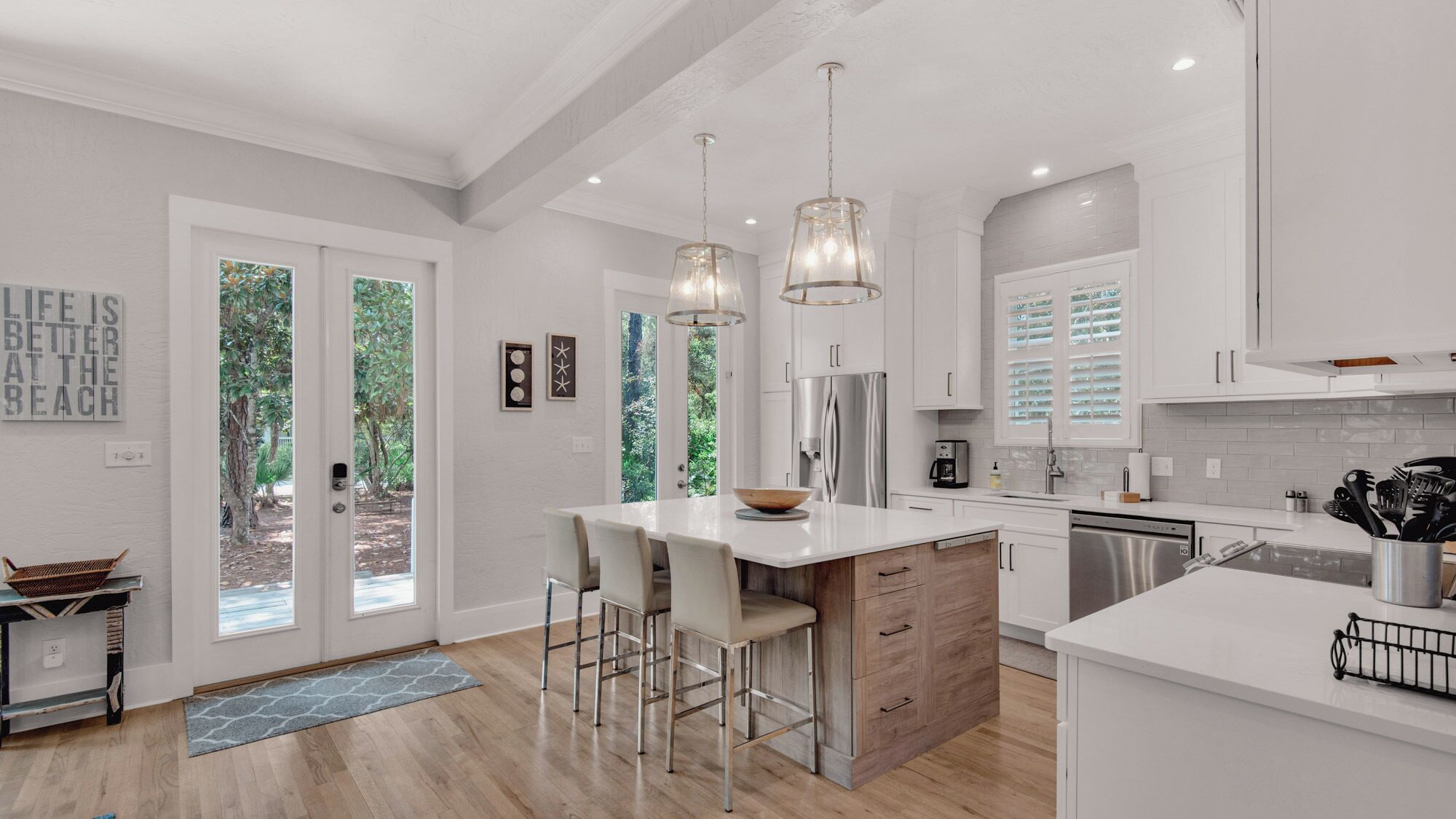 A modern kitchen with white cabinetry, stainless steel appliances, and a large island with bar stools.
