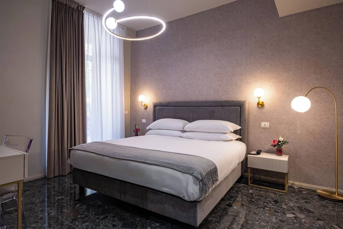 Une chambre d’hôtel moderne, dotée d’un grand lit, d’un bureau et d’une table de chevet avec une lampe.