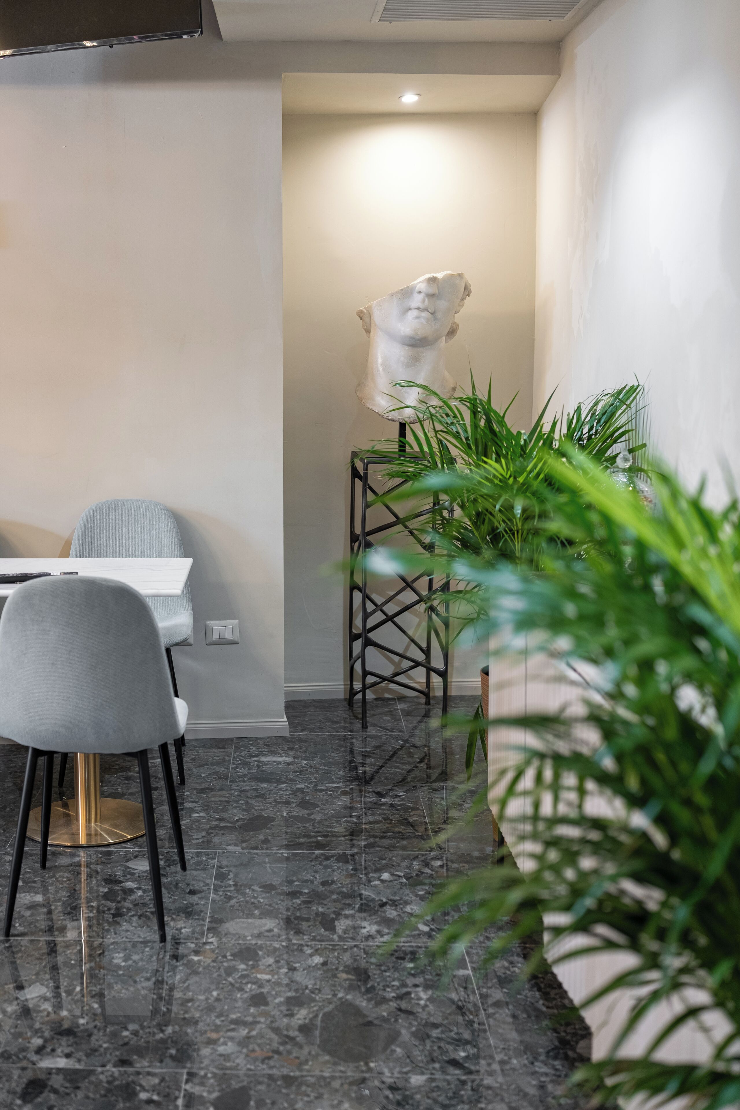 A modern dining area with a marble floor, a white table, and grey chairs.