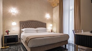 A bedroom with a large bed, two bedside tables with lamps, a nightstand, a chair, and a desk. - Roma Suite Hotel (Rome)