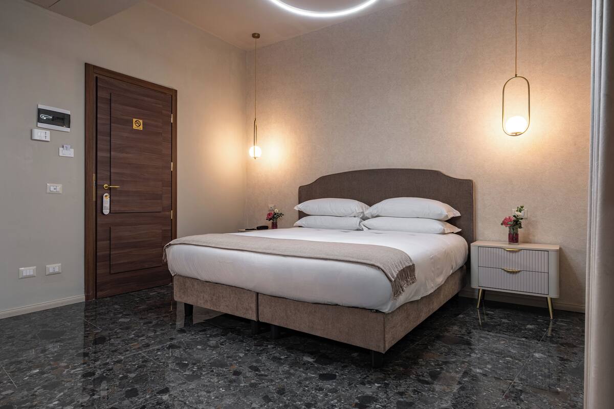 Une chambre à coucher moderne avec un lit, des tables de chevet, une porte et un luminaire.